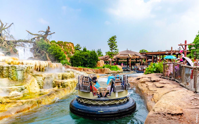 Raft on water ride at Shanghai Disneyland with waterfall and spectators.