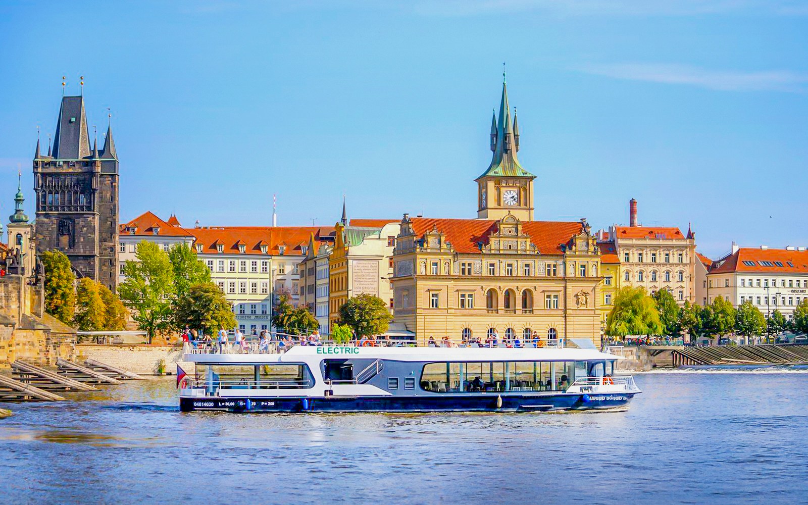 Vltava River cruise boat passing under Charles Bridge in Prague.