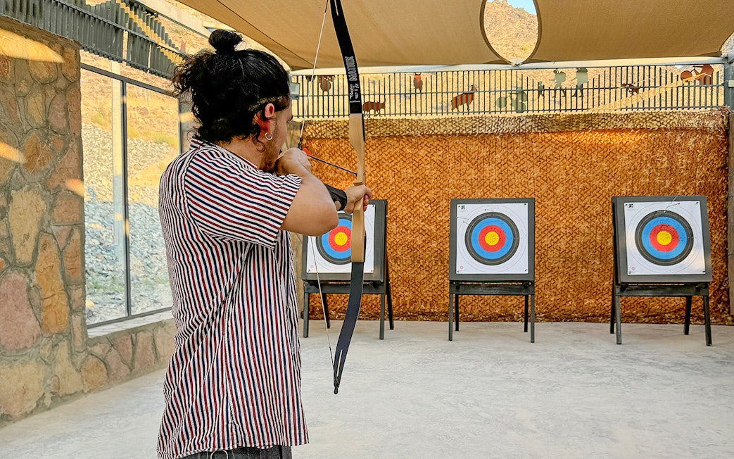 Person practicing archery at Fujairah Adventure Park with targets in view.