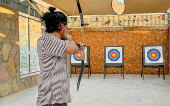 Person practicing archery at Fujairah Adventure Park with targets in view.