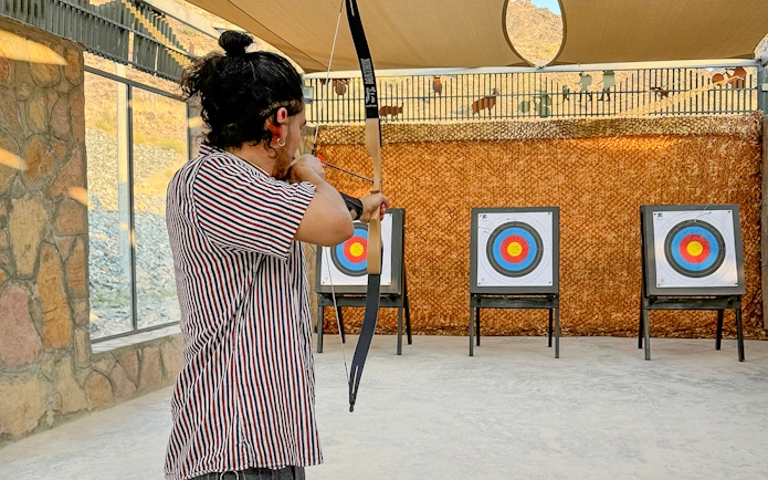Person practicing archery at Fujairah Adventure Park with targets in view.