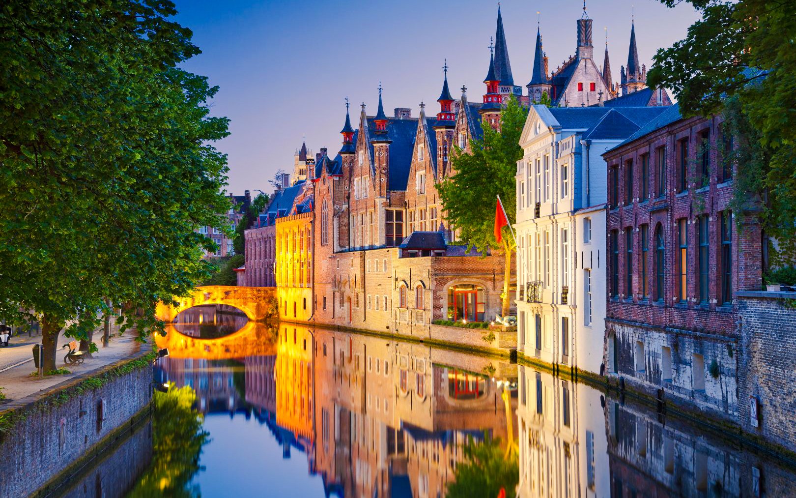 Brugge canals reflecting historic buildings at dusk.