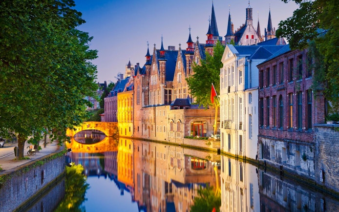 Brugge canals reflecting historic buildings at dusk.