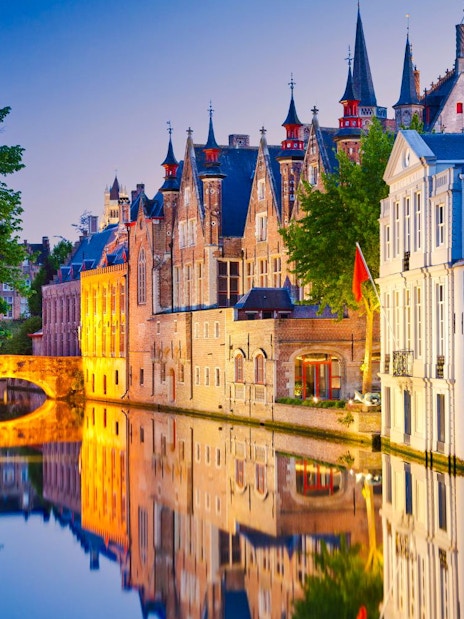 Brugge canals reflecting historic buildings at dusk.