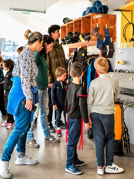 Visitors exploring diving equipment at Cosquer Cave exhibit in Marseille.