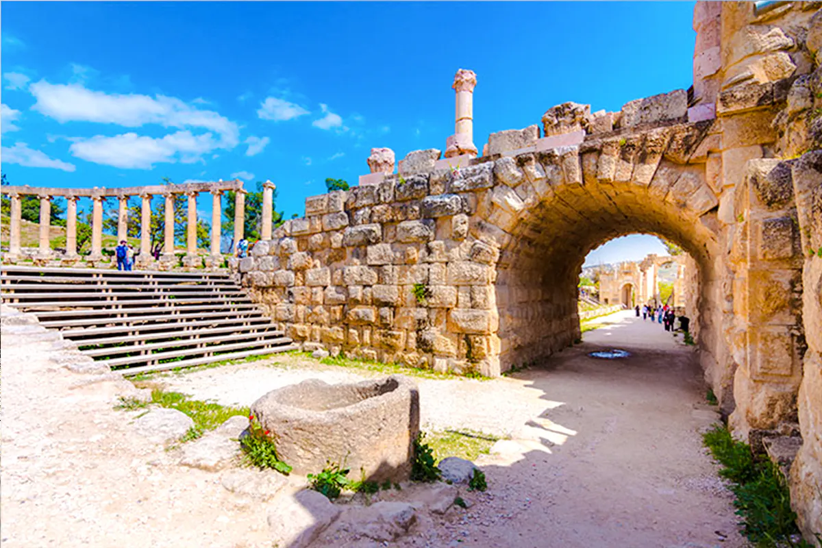 Roman ruins in Jerash with stone archway and columns, part of Amman day trip tour.