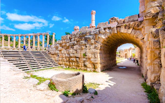 Roman ruins in Jerash with stone archway and columns, part of Amman day trip tour.