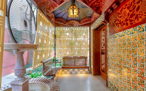 Casa Vicens interior with decorative tiles, wooden bench, and intricate ceiling design.