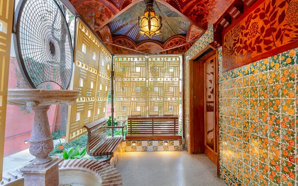 Casa Vicens interior with decorative tiles, wooden bench, and intricate ceiling design.
