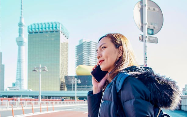 Person using phone with Tokyo Skytree in the background, Japan.