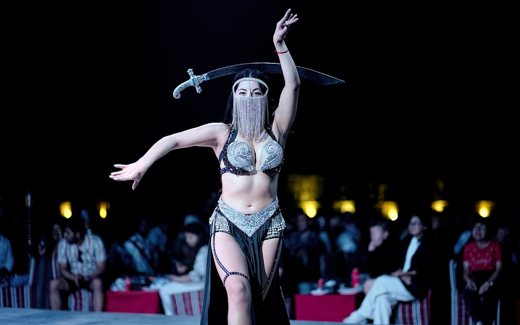 Belly dancer performing with a sword during an evening desert safari show.