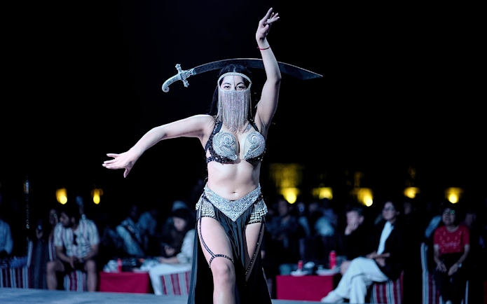 Belly dancer performing with a sword during an evening desert safari show.