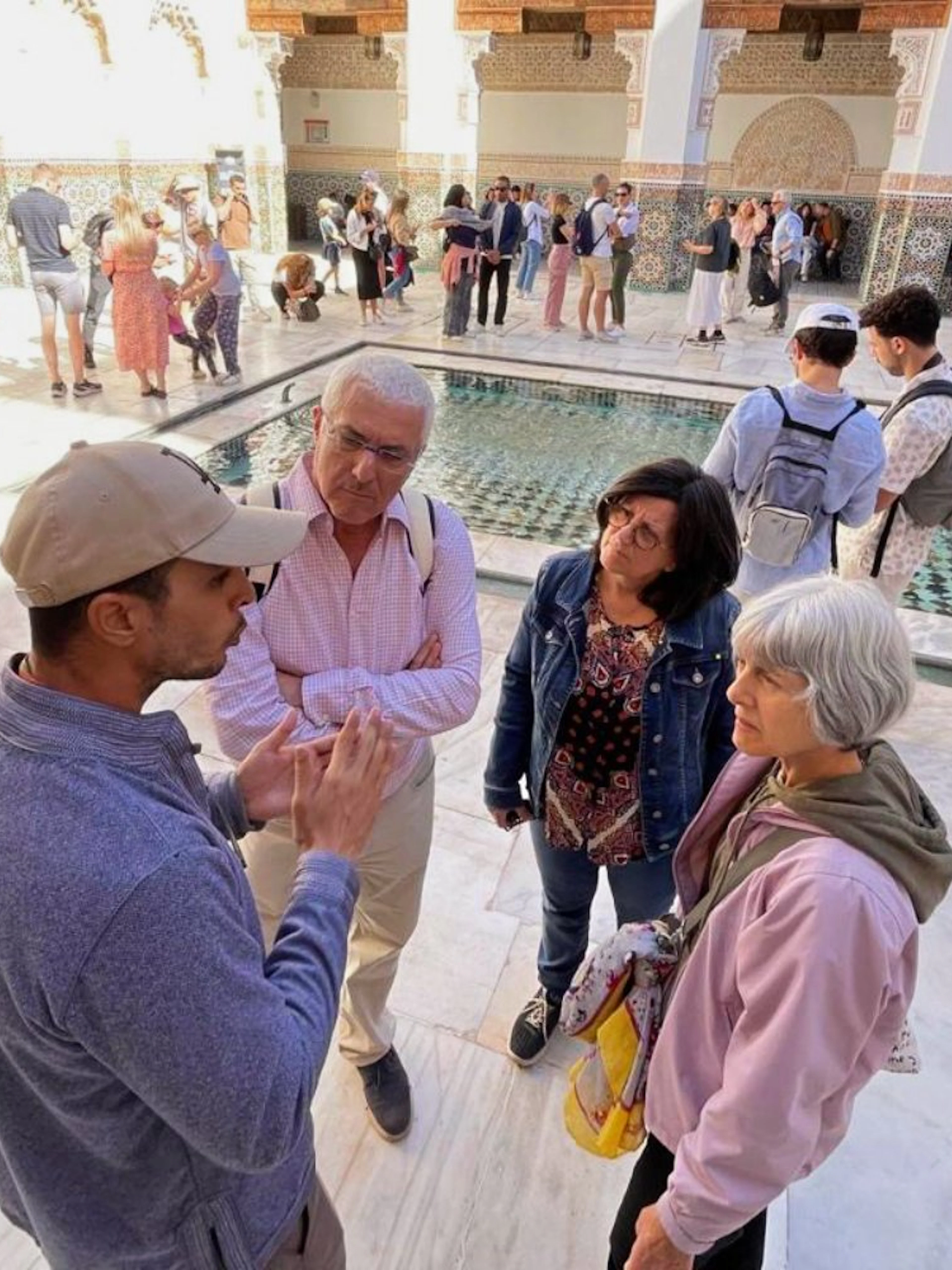 Tour group listening to a guide at Ben Youssef Medersa, Marrakech.