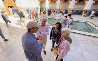 Tour group listening to a guide at Ben Youssef Medersa, Marrakech.
