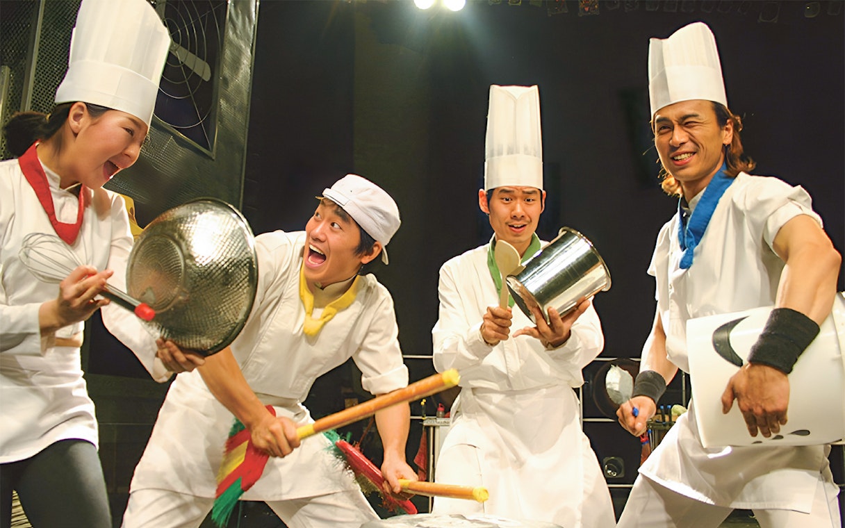 Performers in chef outfits playing kitchen instruments at Seoul Myeongdong Nanta Musical Show.