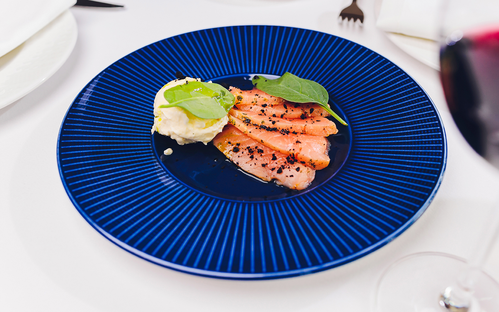 Salmon gravlax with horseradish dip on a blue plate.
