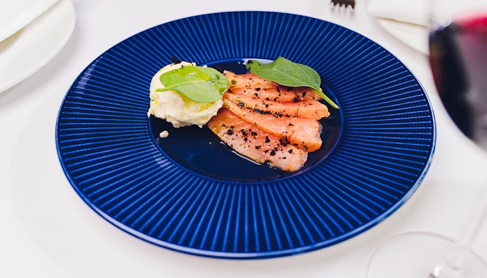 Salmon gravlax with horseradish dip on a blue plate.