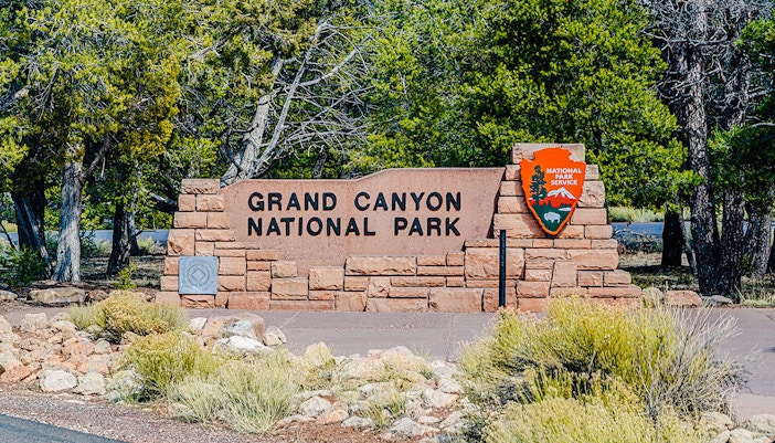 Grand Canyon National Park entrance sign with surrounding desert landscape.