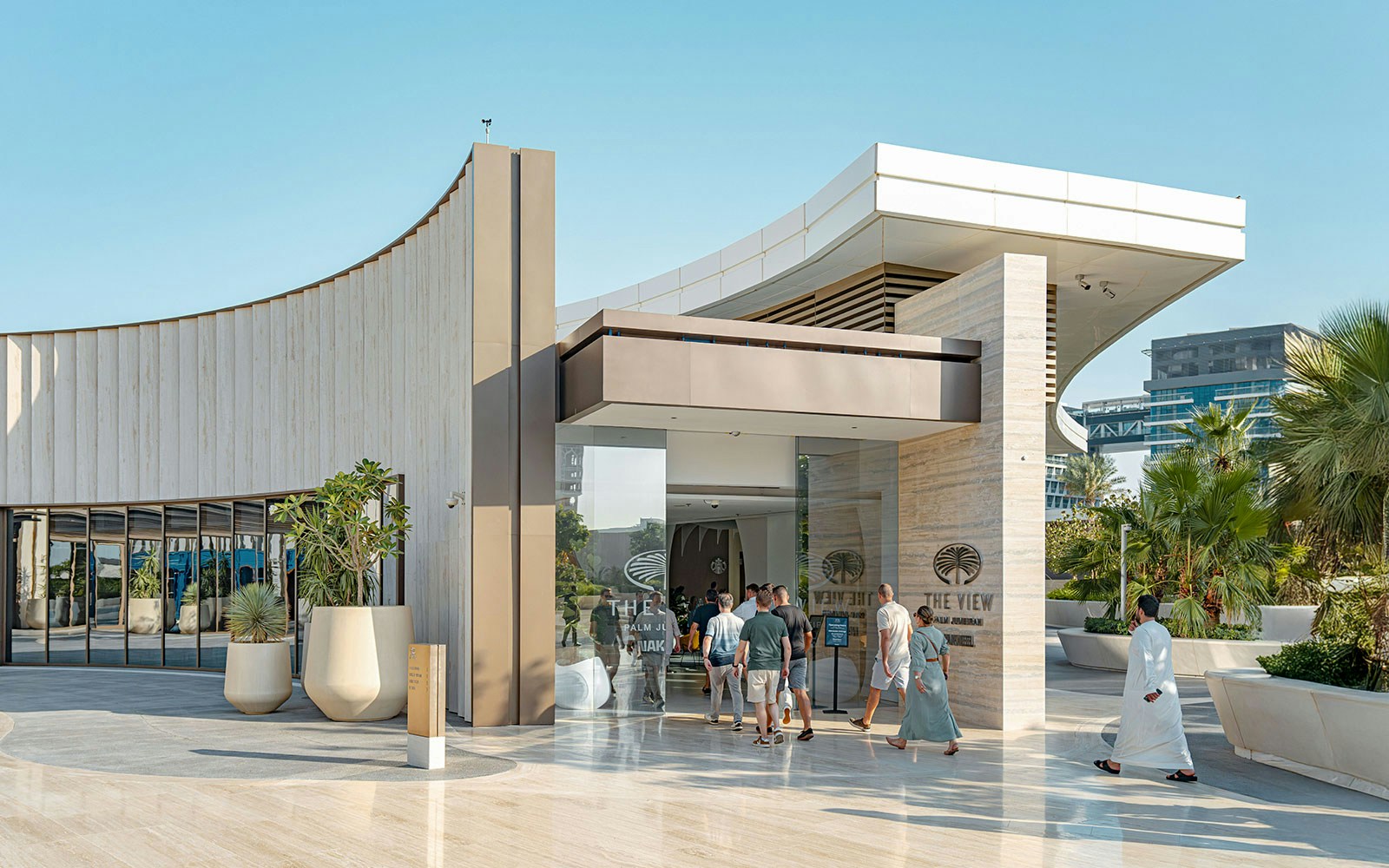 Visitors entering The View at The Palm in Dubai, with modern architecture and palm trees.