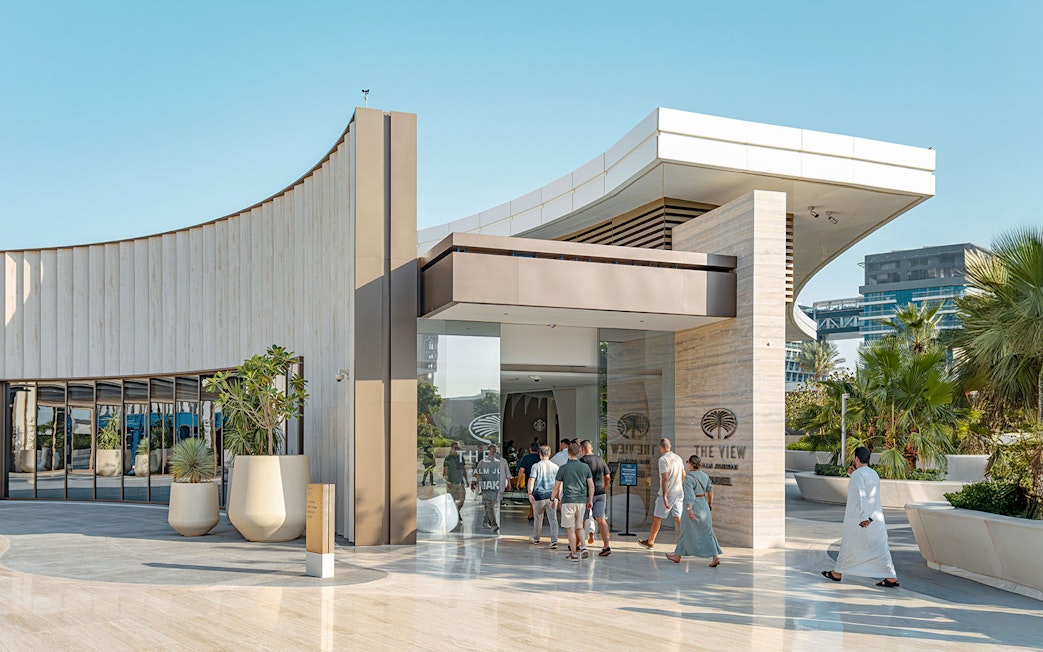 Visitors entering The View at The Palm in Dubai, with modern architecture and palm trees.