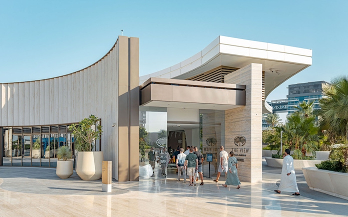 Visitors entering The View at The Palm in Dubai, with modern architecture and palm trees.