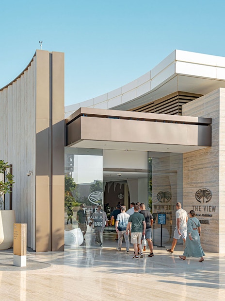 Visitors entering The View at The Palm in Dubai, with modern architecture and palm trees.