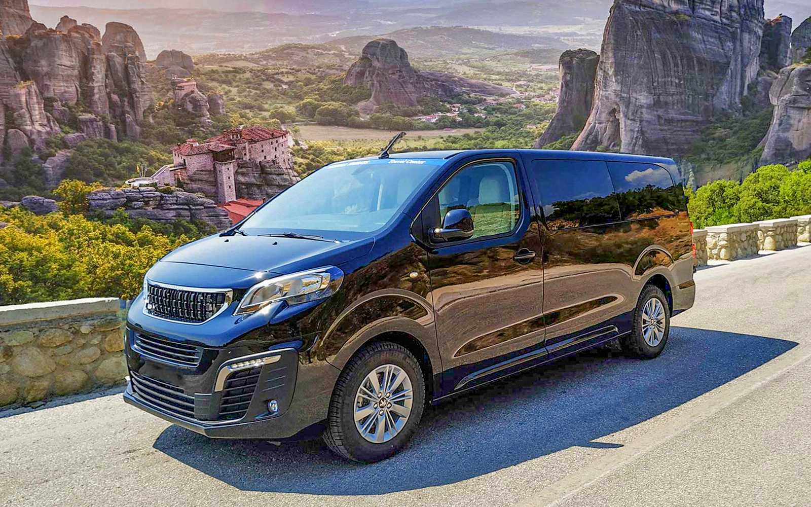 VIP van parked with Meteora rock formations in Greece in the background.