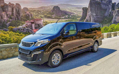 VIP van parked with Meteora rock formations in Greece in the background.