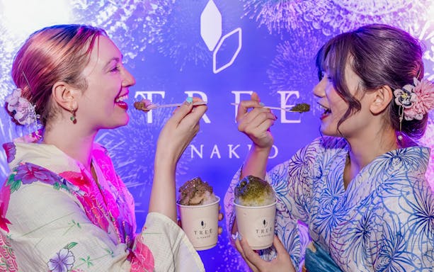 Two people in traditional attire enjoying shaved ice at NAKED Summer Festival 2024, Nijo-jo Castle.