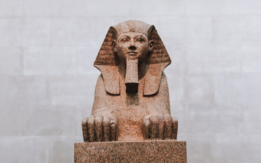Granite statue of the Sphinx of Hatshepsut in a museum setting.