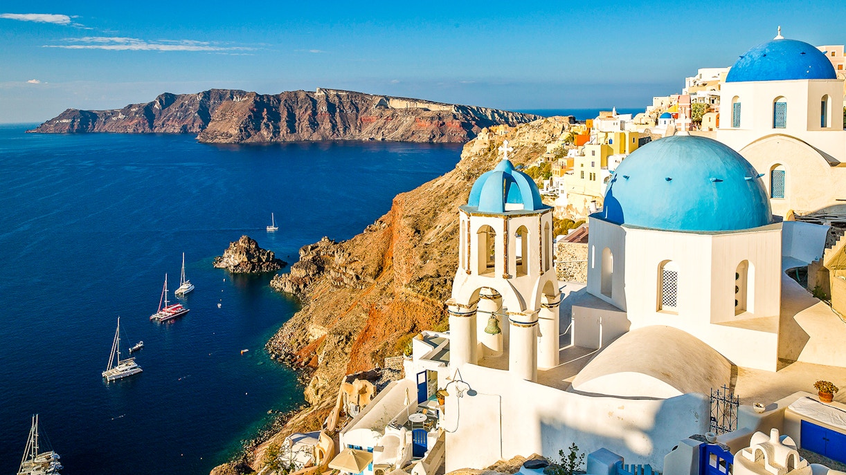 Whitewashed buildings and blue-domed churches in Oia, Santorini, overlooking the Aegean Sea.