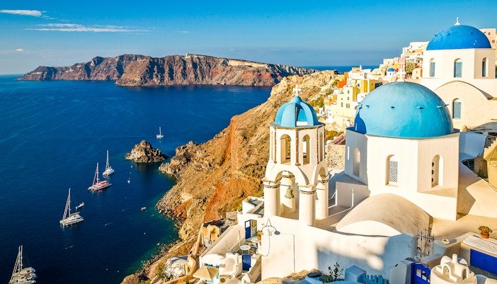 Whitewashed buildings and blue-domed churches in Oia, Santorini, overlooking the Aegean Sea.