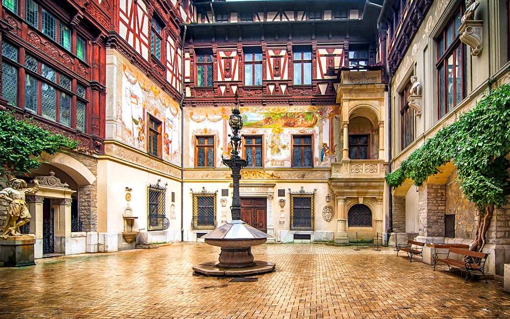 Inner courtyard of Peles Castle with ornate architecture and central fountain.