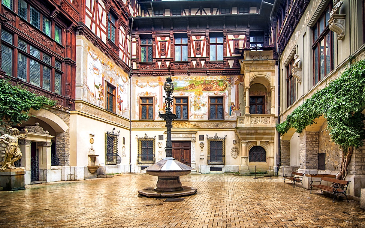 Inner courtyard of Peles Castle with ornate architecture and central fountain.