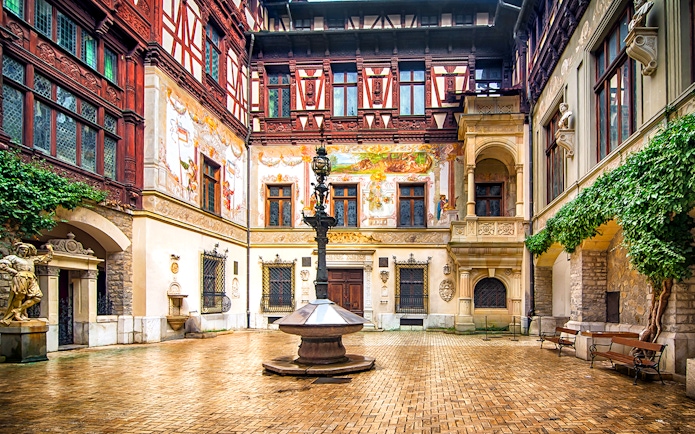 Inner courtyard of Peles Castle with ornate architecture and central fountain.