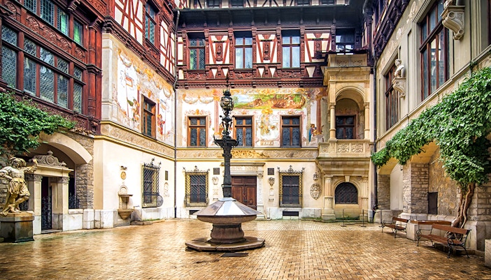 Inner courtyard of Peles Castle with ornate architecture and central fountain.