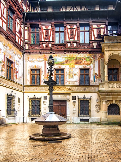 Inner courtyard of Peles Castle with ornate architecture and central fountain.