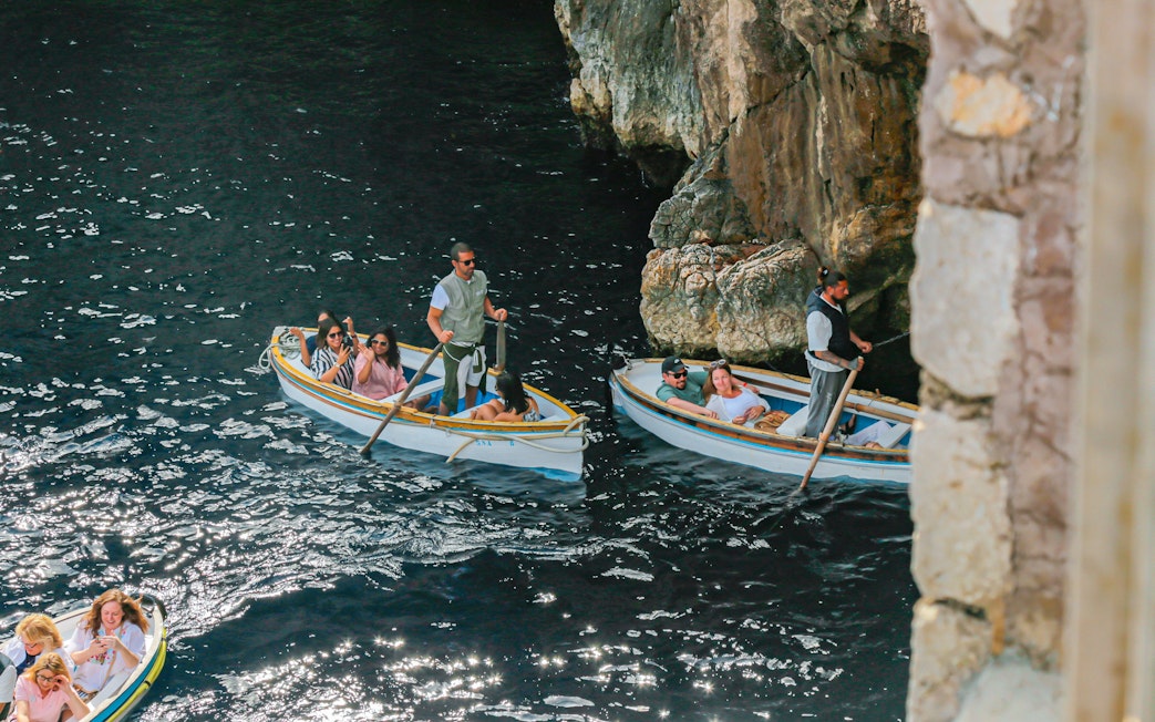 Tourists with guide in rowboats entering Blue Grotto, Capri, Italy.