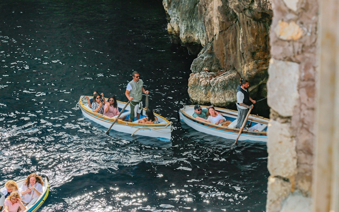 Tourists with guide in rowboats entering Blue Grotto, Capri, Italy.