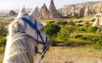 Horseback riding at sunrise with view of Cappadocia's rock formations.