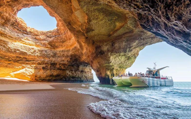 Catamaran with tourists entering Benagil Caves, Algarve, Portugal.