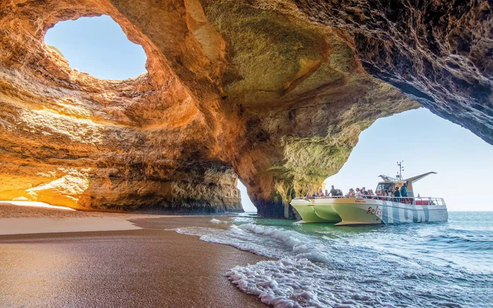 Catamaran with tourists entering Benagil Caves, Algarve, Portugal.