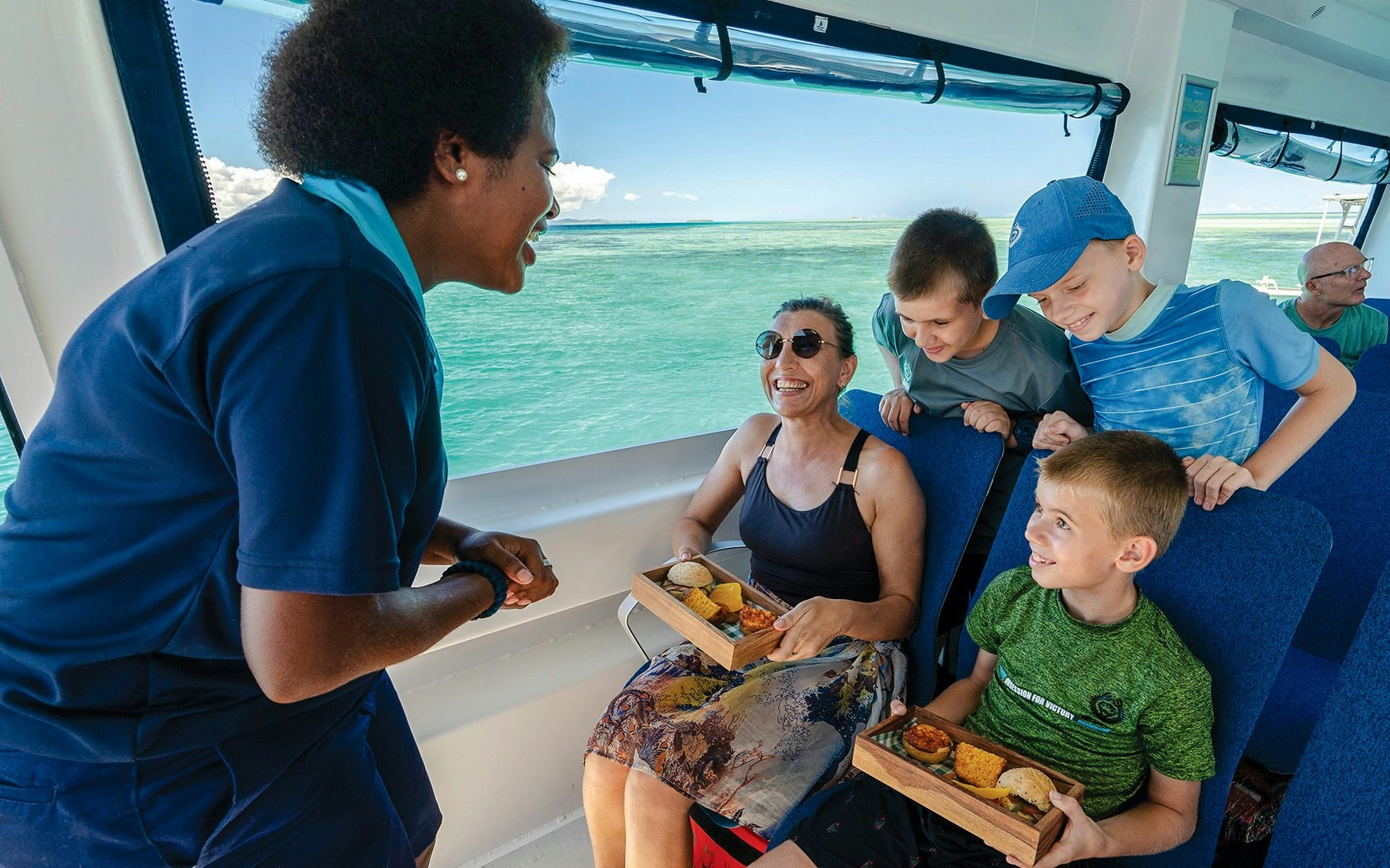 Staff member serving guests on a boat, South Sea Cats, Fiji.