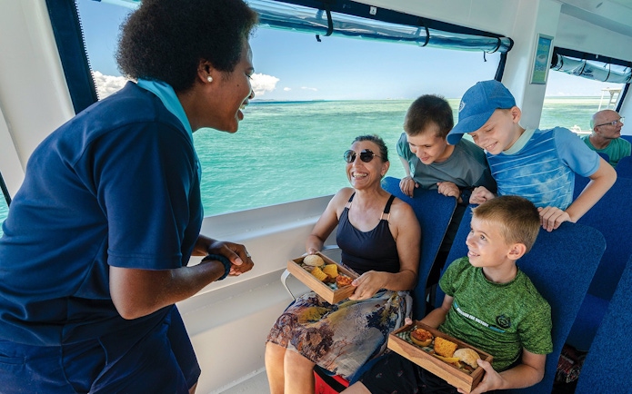 Staff member serving guests on a boat, South Sea Cats, Fiji.