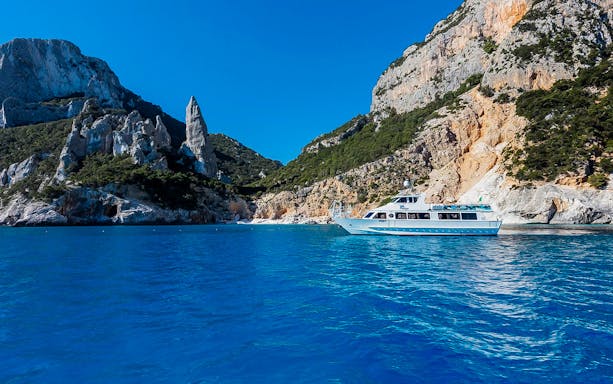 Cruise boat on Gulf of Orosei with rocky cliffs near Cala Gonone.
