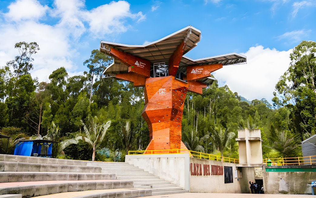 Climbing wall at Salt Cathedral of Zipaquirá, Colombia, surrounded by lush greenery.