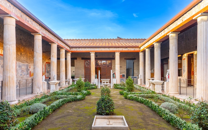 Pompeii garden with ancient columns and greenery in Italy.