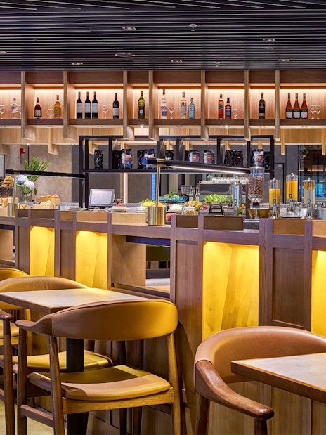 Plaza Premium Lounge seating and bar area at KLIA Terminal 2 with departure board.