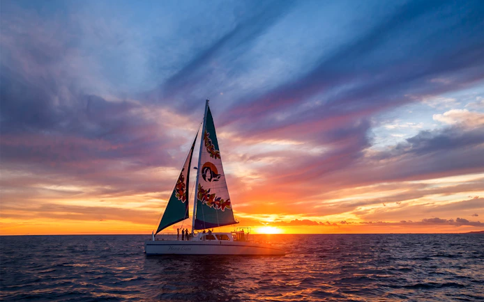 Sailboat on West Oahu sunset sail with vibrant sky and ocean.