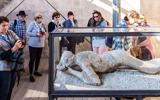 Visitors observing a plaster cast of a volcano victim in Pompeii.
